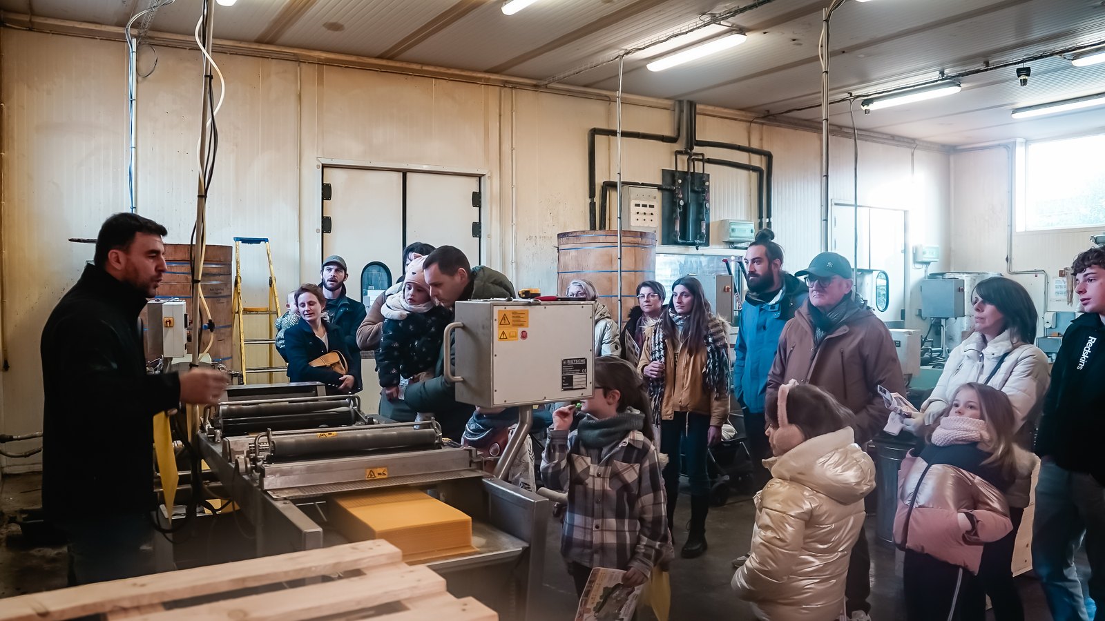 Des visiteurs de tous âges assistent à une démonstration dans l’atelier d’Apiculture Remuaux lors des portes ouvertes