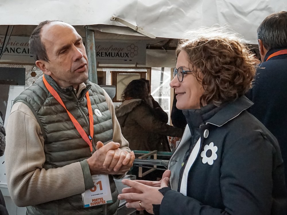 Deux visiteurs échangent devant l’atelier de gaufrage pendant la journée des apiculteurs 2025