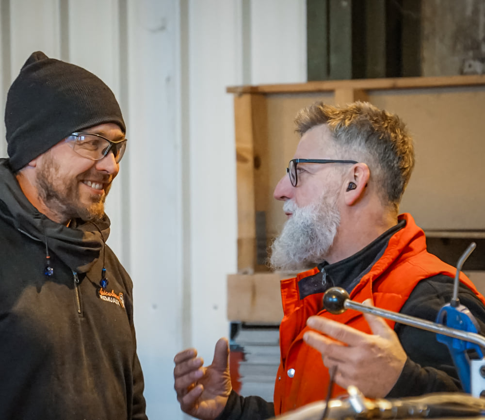 Deux professionnels échangent devant une machine dans l’atelier de menuiserie