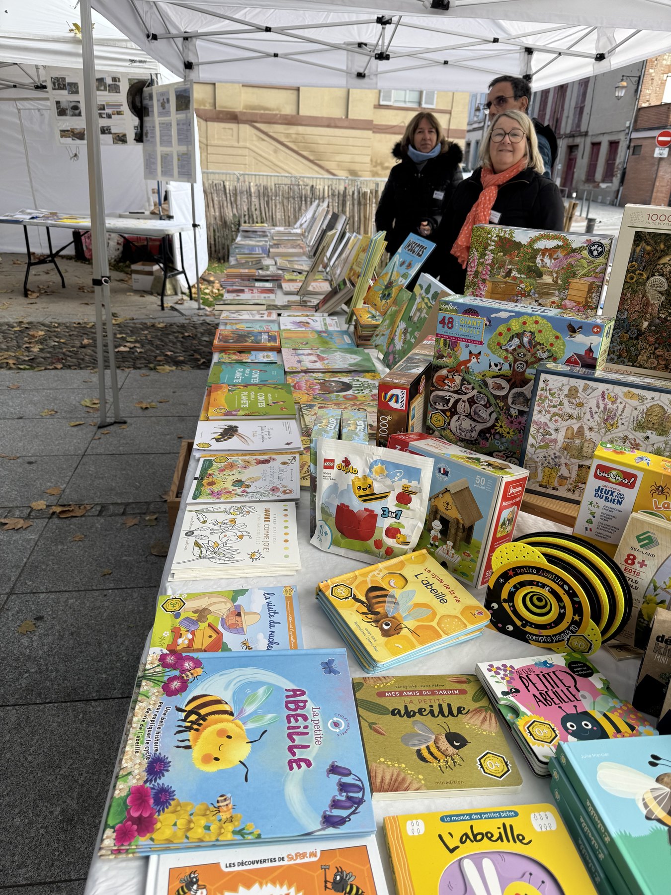 Anne et la sélection de livres, jeux et puzzles présentée au stand de la foire au miel d’Albi